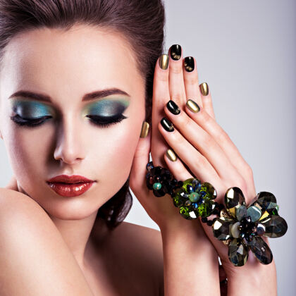 眼睛美丽的女人脸 绿色的化妆品和玻璃首饰 创意指甲优雅在手漂亮