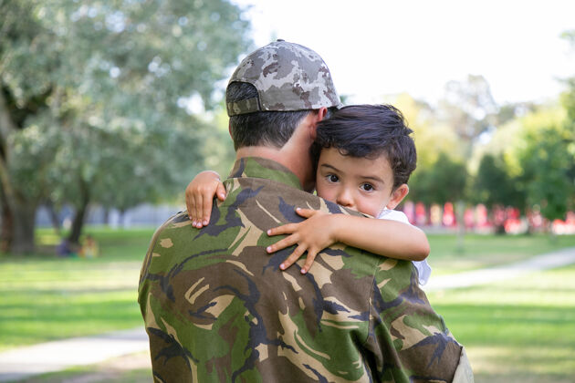 父母中年父亲抱着儿子的背影可爱的小男孩抱着穿军装的爸爸 望着别处孩子帽子儿子