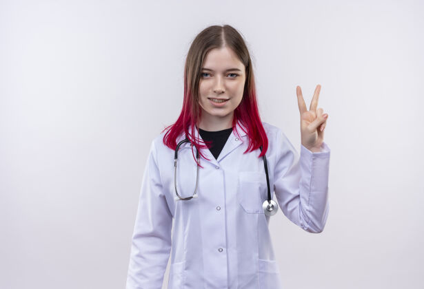 医生穿着听诊器医用长袍的年轻医生女孩很高兴 在孤立的白色背景上表现出和平的姿态和平高兴白人