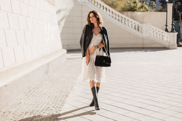 手提包年轻时尚的女人穿着时髦的服装走在街上 拿着钱包 穿着黑色皮夹克和白色蕾丝连衣裙 春秋风格 摆姿势 高高的皮靴钱包皮革包