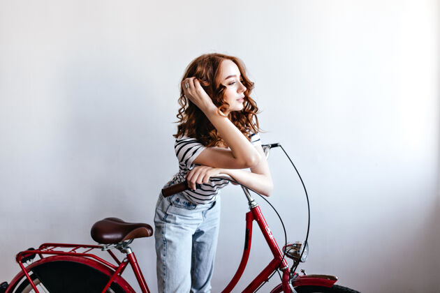 欧洲沉思的红发女模特与自行车合影室内拍摄迷人的卷发女子站在自行车旁边波浪人室内