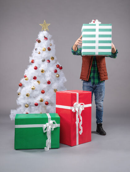 盒子年轻的男性在灰色的圣诞礼物周围包男性礼物