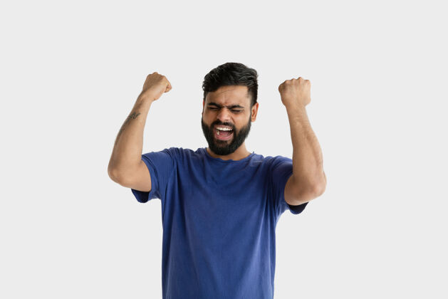 情感美丽的男性肖像年轻情绪化的印度教男子穿着蓝色衬衫面部表情 人类的情感庆祝像一个赢家肖像人手势