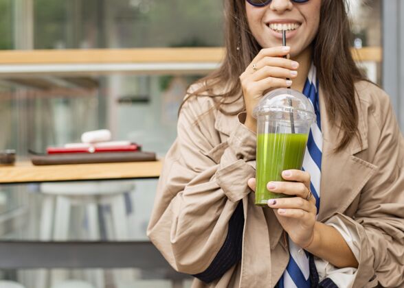 果汁快乐的女人喝着绿色的冰沙健康食品美味食品