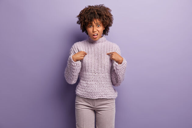 皱眉愤愤不平的年轻女子指着自己 问为什么这是她的职责 不高兴地皱眉 表示不同意 穿着针织毛衣 隔着紫色的墙为什么是我？风格非洲表情