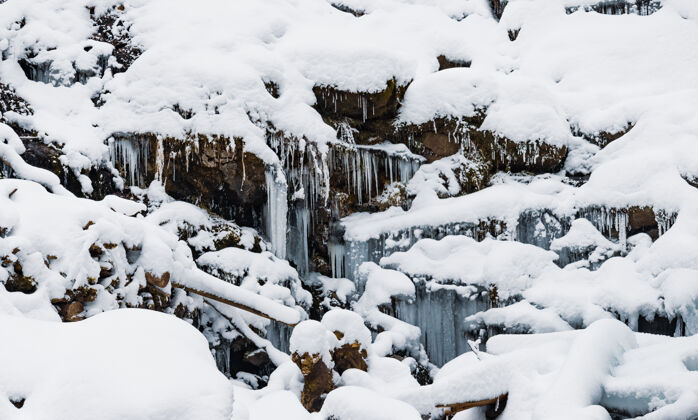 雪地冰水的小山瀑在白雪覆盖的湿石头间流动河流流喷雾