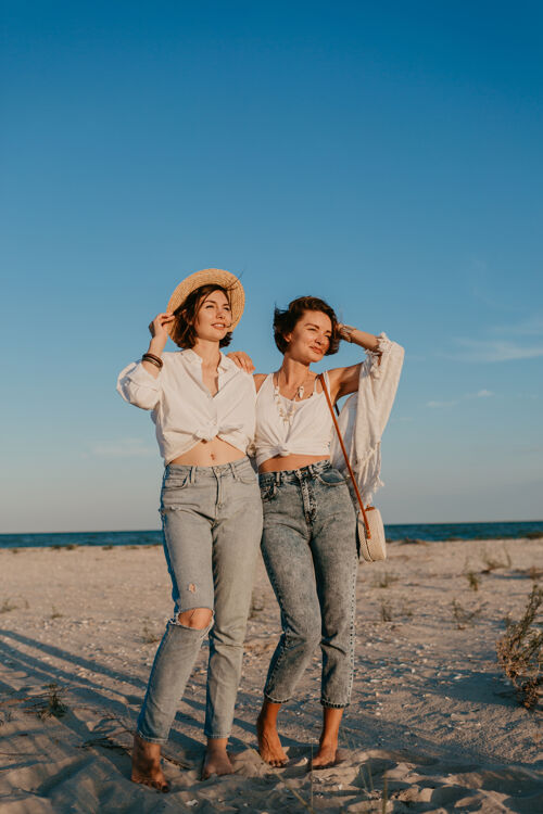 伴侣酷酷的两个年轻女子在日落海滩上玩得很开心 男女同性恋的爱情浪漫女人年轻女同性恋