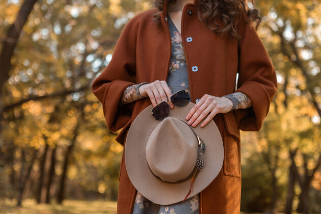 优雅特写手的细节有吸引力的时髦女人拿着帽子和太阳镜在公园散步穿着暖和的外套秋天时髦的街头时尚风格配件女人休闲穿着