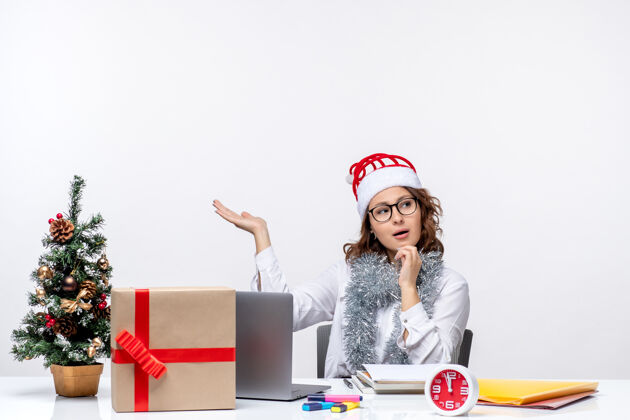 思考正面图：年轻的女工坐在她工作的地方 在白色的背景下沉思商务前面圣诞节