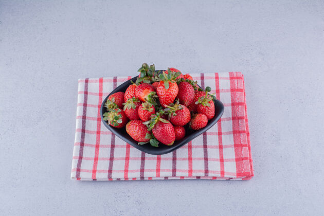 营养黑色的碗 大理石背景上有一堆草莓健康有机美味
