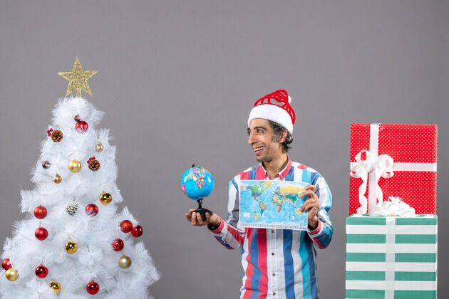 圣诞节正面图幸福的人与螺旋弹簧圣诞帽举行世界地图和地球仪有趣印刷家伙