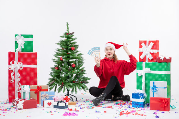 快乐前视图年轻女子围坐在白墙上拿着飞机票的礼物冬天旅行圣诞快乐