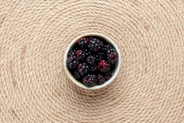 接近在粉红色书桌上的白色小锅里俯瞰新鲜的黑莓新鲜小水果