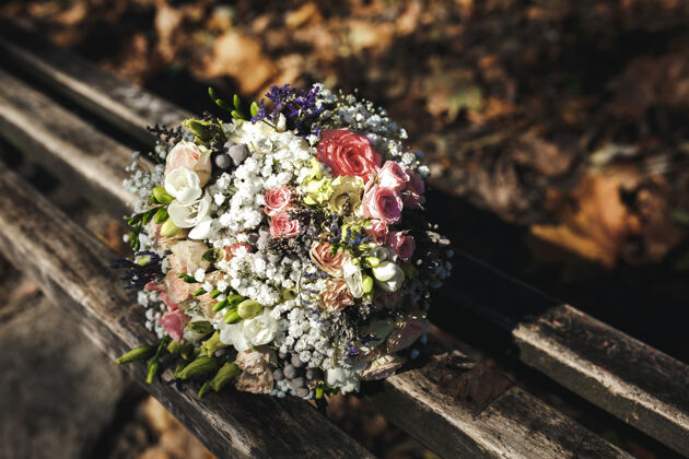 美丽美丽的新娘花束躺在公园的长椅上 秋天的婚礼树叶树叶乡村