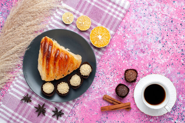 茶在粉红色的表面上放着肉桂 茶和巧克力糖的糕点片的俯视图巧克力烘焙糖果