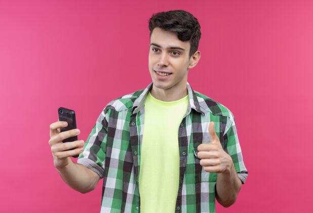 向上微笑的白人年轻人穿着绿色衬衫 在孤立的粉色背景上举着大拇指粉色绿色小伙子