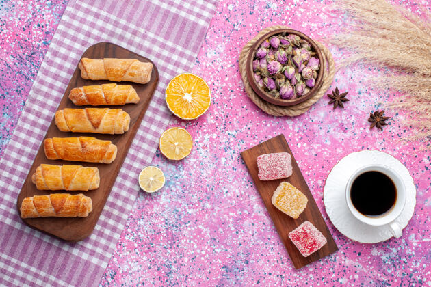 百吉饼在粉红色的桌子上可以俯瞰一杯带有果酱片和百吉饼的茶糖杯子盘子