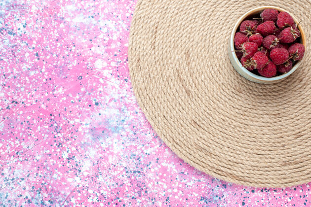 新鲜在粉红色书桌上的小锅里俯瞰新鲜的红莓水果织物盆栽