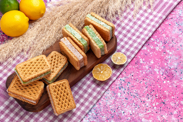 果仁半俯瞰美味的三明治饼干与柠檬和肉桂在粉红色的办公桌上粉色谷物肉桂
