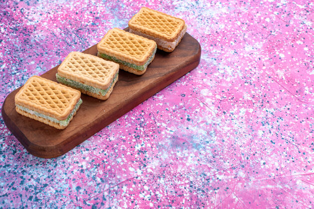 奶油正面图：粉色背景上填充水果奶油的华夫饼干巧克力棕色茶