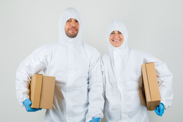 医药两个医生穿着防护服 戴着手套拿着纸板箱 看上去很高兴站立制服妇女