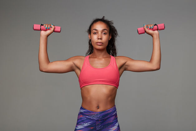 摆姿势运动型黑皮肤女人 棕色卷发 站着锻炼双手 穿着运动服粉色有色非洲