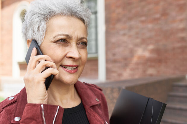 退休漂亮自信的中年商业女性在手机上讲话的户外写真城市通讯街道