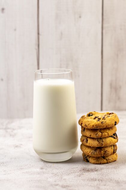 饮料桌子上一杯牛奶旁一堆巧克力饼干的垂直镜头早餐圆形堆叠