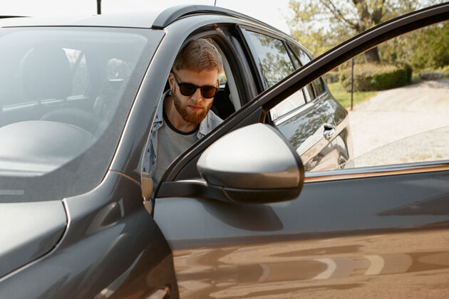 交通自信的年轻胡须男子戴着时髦的太阳镜开车旅行金融交通