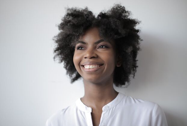 美国人美丽的非洲裔美国女性站在白色的墙上 面带微笑表情风格孤独