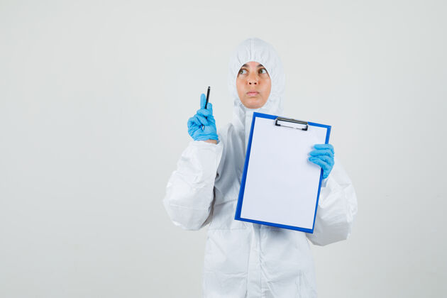 实验室女医生指着 手里拿着写字板和笔 穿着防护服女人年轻人医生