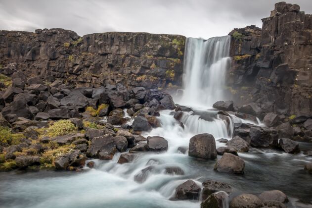 河流Oxararfoss瀑布在thingvellir 冰岛在乌云密布的天空下岩石草户外