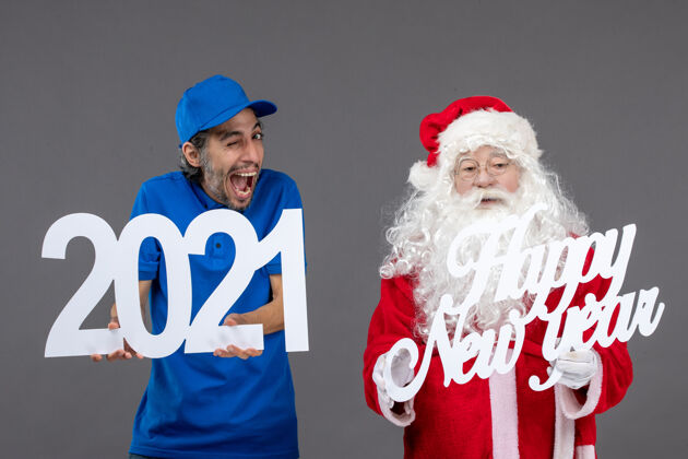 工人圣诞老人与男信使举行和新年快乐和2021年板灰墙的正面视图圣诞老人前面节日