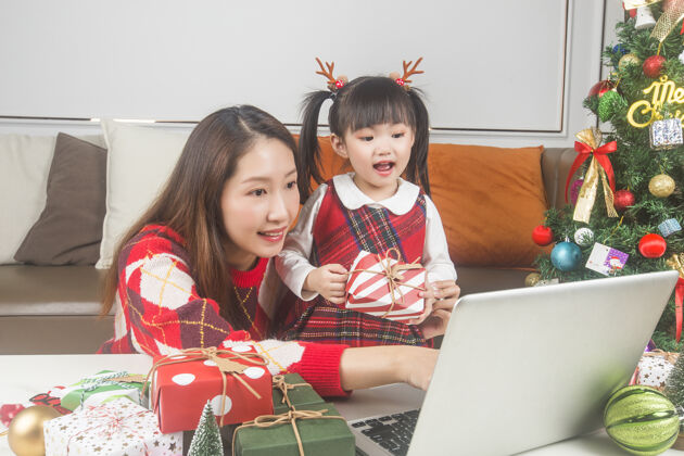女孩快乐的妈妈和小女儿在家装饰圣诞树和礼物孩子母亲母亲