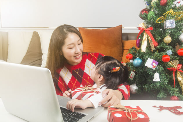 房子快乐的妈妈和小女儿在家装饰圣诞树和礼物中国爱冬天