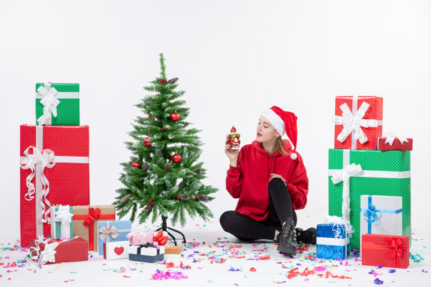 人前视图：年轻女子围坐在白色墙壁上拿着礼物节日圣诞快乐十二月