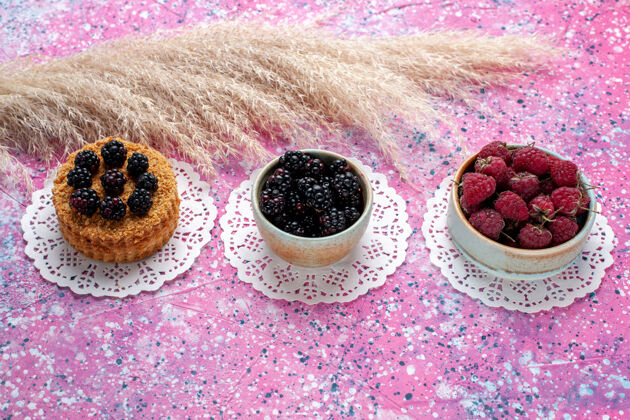 黑莓前视图小黑莓蛋糕与覆盆子和新鲜黑莓淡粉色背景新鲜食物黑莓