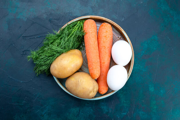 绿色在深蓝色的桌子上俯瞰胡萝卜和土豆 还有鸡蛋和蔬菜番茄胡萝卜午餐