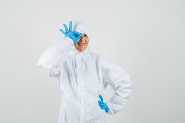 妇女女医生穿着防护服 戴着手套 眼睛上显示ok标志 看起来很滑稽套装专业人员手势