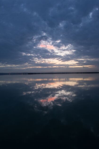 云景日落的天空和风暴云反射在水面上的壮丽景色日出云湖泊