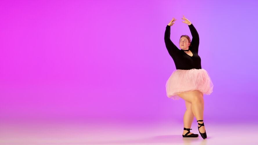 期待美丽的高加索人模特在霓虹灯下的渐变紫粉色工作室背景上练习芭蕾舞激励 包容 梦想和成就的理念值得成为芭蕾舞演员包容加上大小跳跃