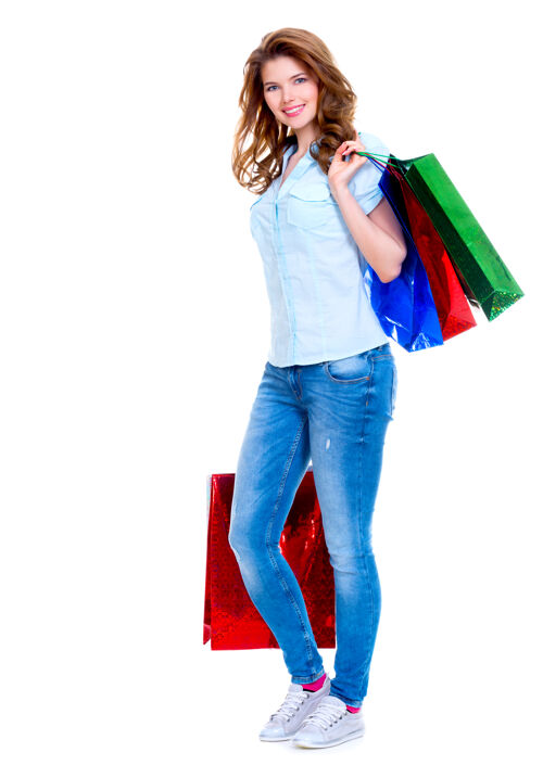 购物美丽快乐的女人 带着蓝色牛仔裤的购物袋 在白色的背景下孤立着漂亮购物者女