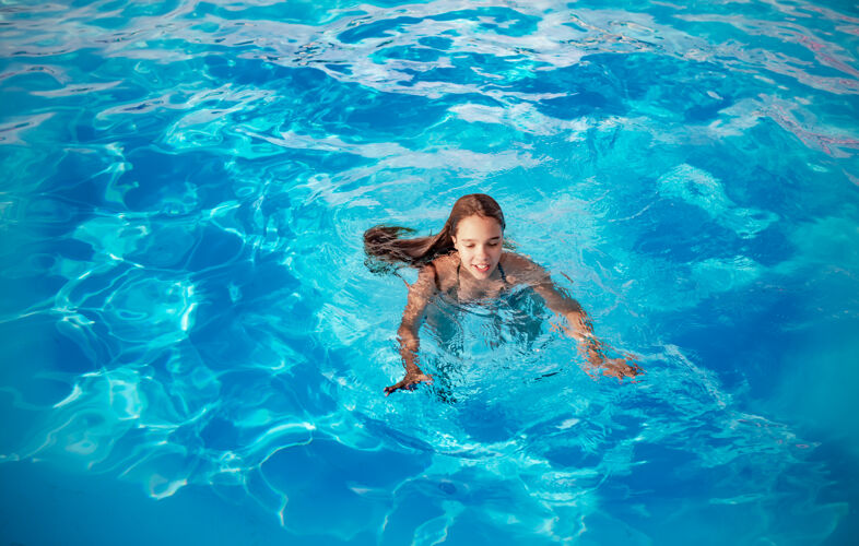童年在一个温暖的热带国家 一个阳光明媚的夏日 一个十几岁的女孩在清澈湛蓝的游泳池里游泳人游泳池婴儿
