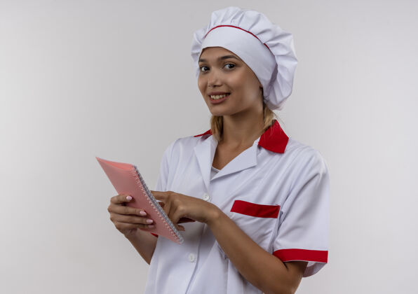 女性微笑着的年轻厨师 穿着厨师制服 把手指放在手里的笔记本上手指手笔记本