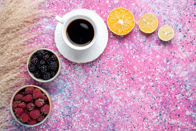浅粉色顶视图的树莓和黑莓内的小茶壶茶杯浅粉红色的表面水果黑莓杯子