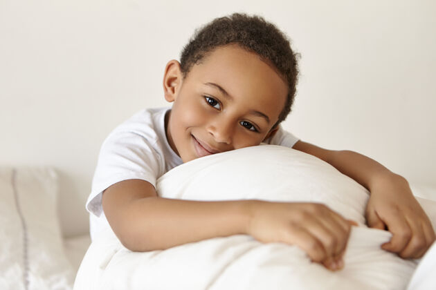 甜蜜快乐可爱的黑皮肤非洲裔男孩在床上放松周末醒来后床梦非洲