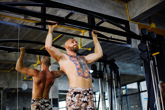 男性纹身的健康男人在健身房锻炼男人拉运动