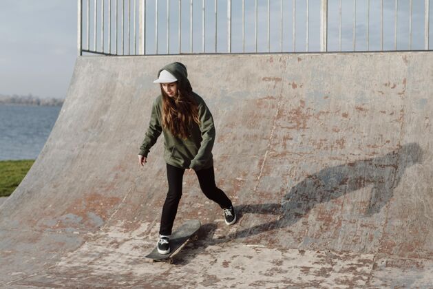 年轻女滑板运动员使用坡道的伎俩生活方式日光城市生活
