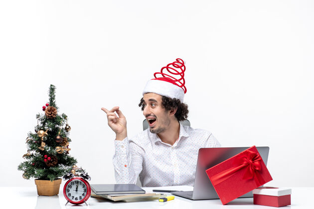 某人带着滑稽的圣诞老人帽子的年轻商人在办公室里和一个白色背景的人说话圣诞老人积极商人