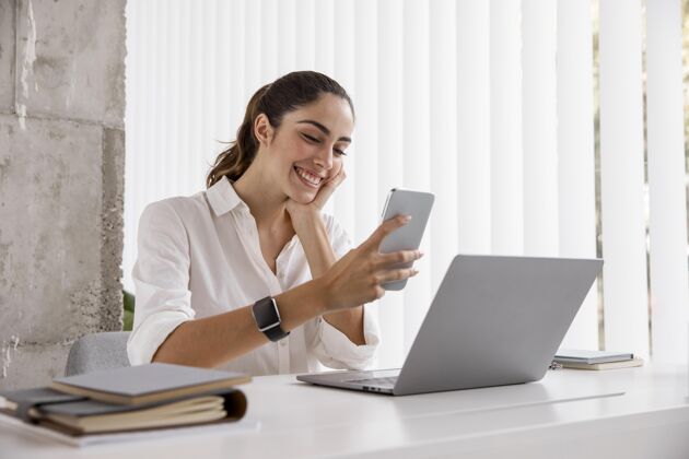 笔记本电脑带智能手机和笔记本电脑的smileybusinesswoman侧视图女商人智能手机个性